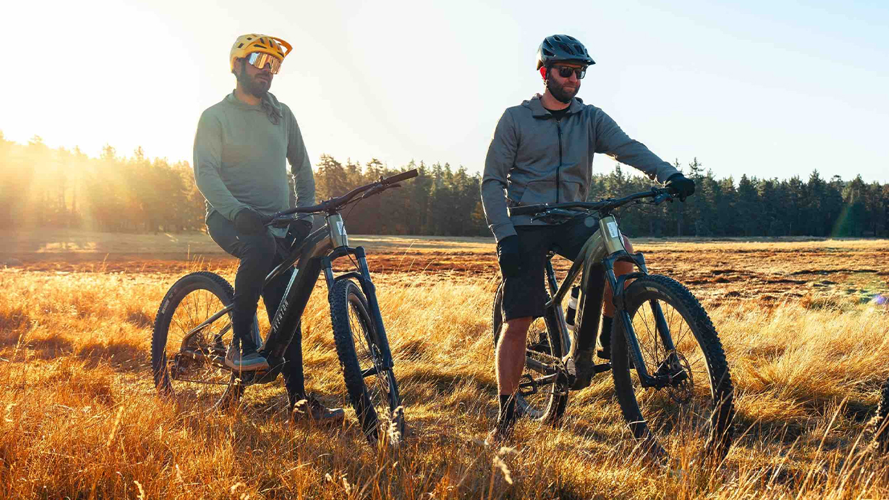 Deux amis faisant du vélo électrique de montagne avec lever de soleil