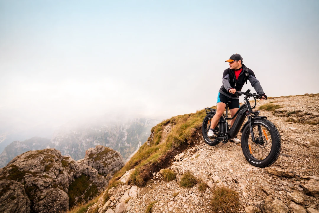 Cycliste sur un vélo électrique Taubik Westridge 4T à pneus larges sur un sentier rocheux en montagne.